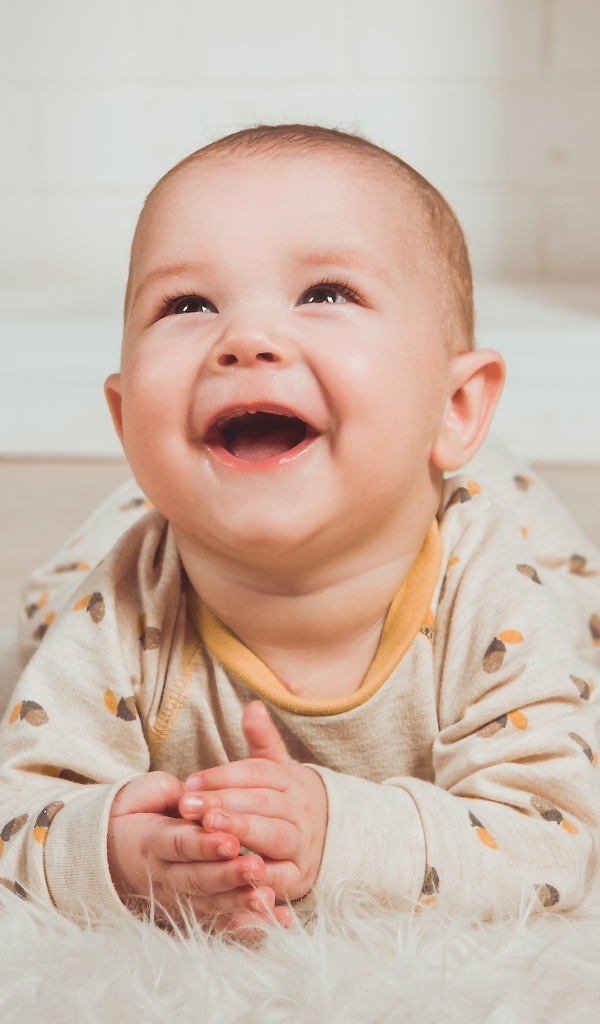 Смеющийся малыш лежит на полу