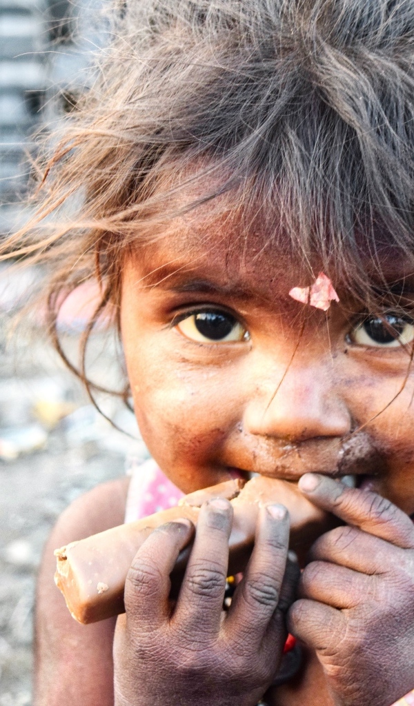 Маленькая азиатская девочка с конфетой в руках