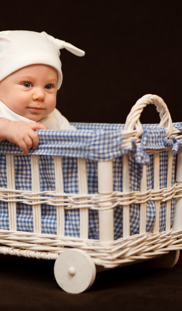 Маленький ребенок в колыбели на коричневом фоне