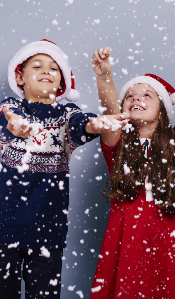 Маленькие мальчик и девочка ловят снег