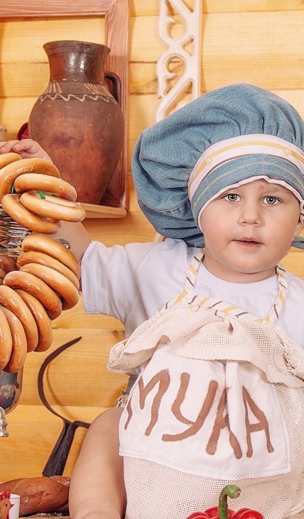 Маленький мальчик повар с продуктами и самоваром на столе