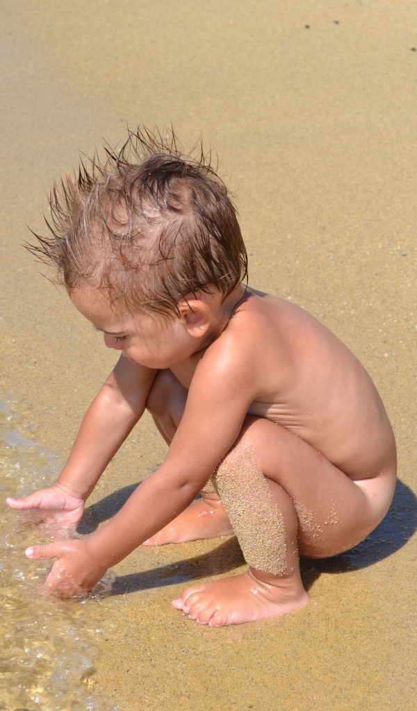 Маленький мальчик на пляже у моря на песке