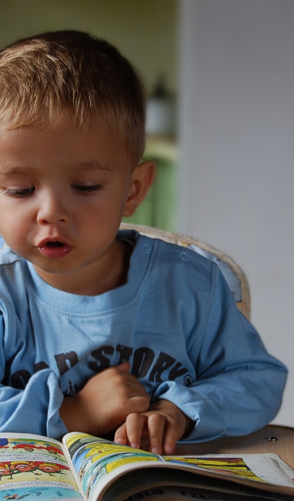 Маленький мальчик читает интересную книгу