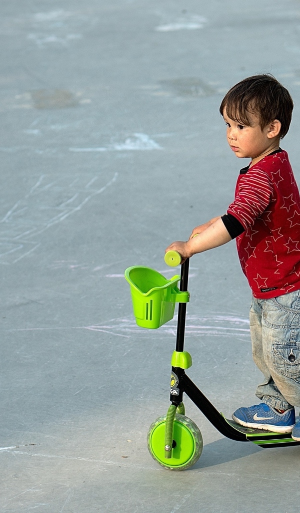 Маленький мальчик с зеленым самокатом
