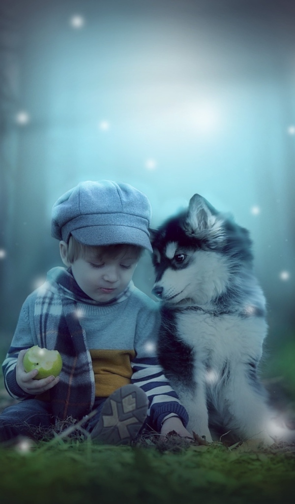 Маленький мальчик с щенком сидят на траве в лесу