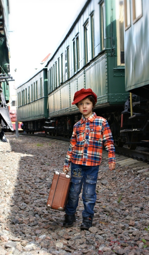 Маленький мальчик с чемоданом у вагонов