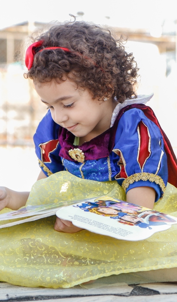 Маленькая девочка в костюме Белоснежки с книгой