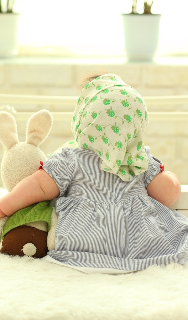 Маленькая девочка обнимает игрушечного зайца