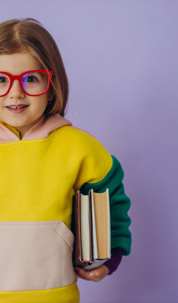 Маленькая девочка в очках с книгами в руке