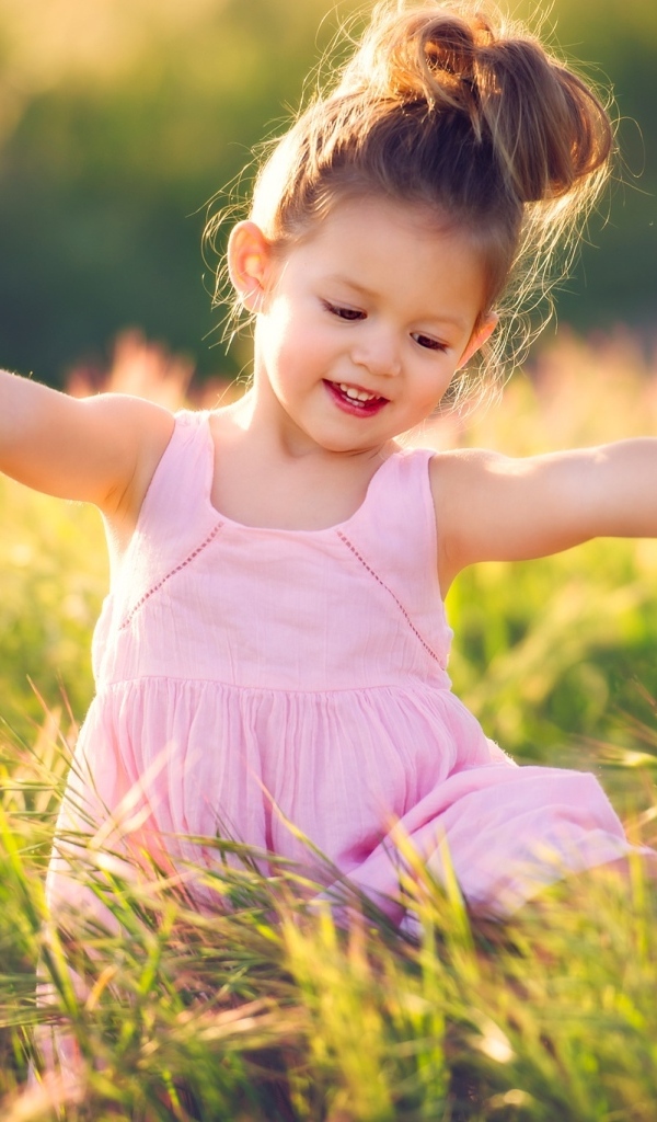 Маленькая девочка в розовом платье в зеленой траве