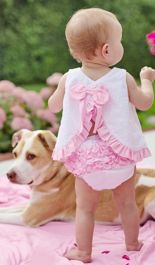 Маленькая девочка с собакой на розовом покрывале