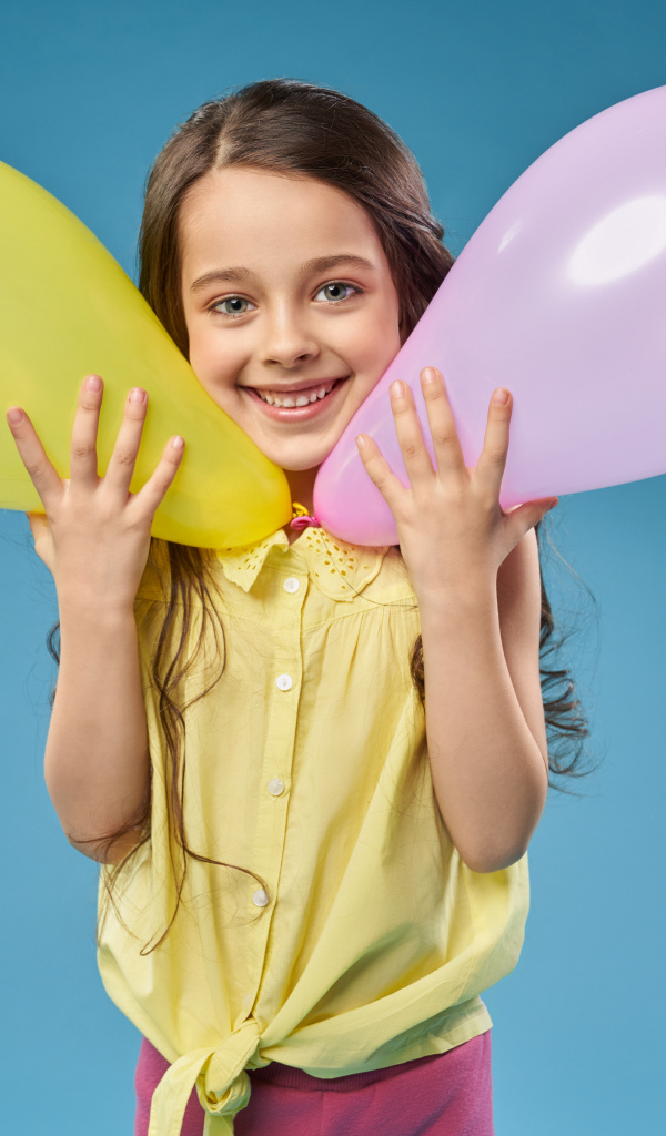 Маленькая девочка с воздушными шариками на голубом фоне