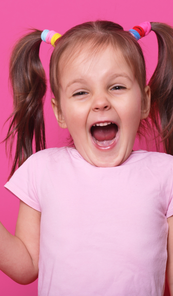 Маленькая девочка с леденцом на розовом фоне