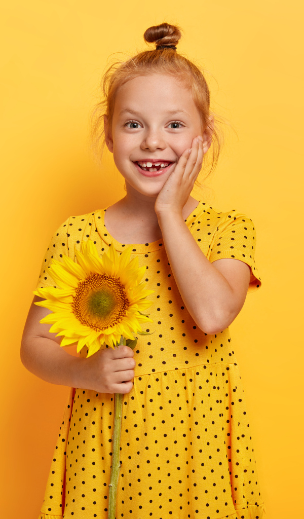 Маленькая рыжеволосая девочка с подсолнухом в руках