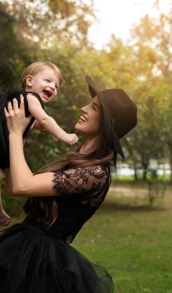 Мама держит улыбающуюся дочь на руках