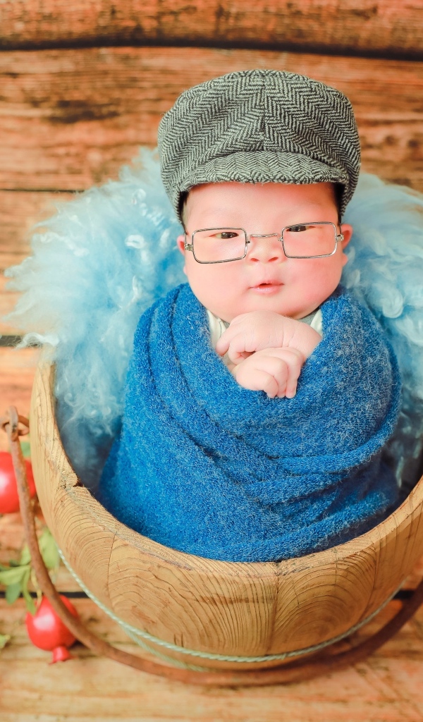 Новорожденный малыш в покрывале с кепкой на голове