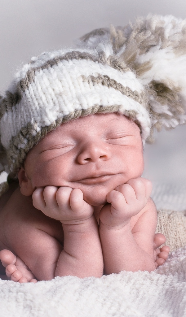 Новорожденный младенец в большой вязаной шапке