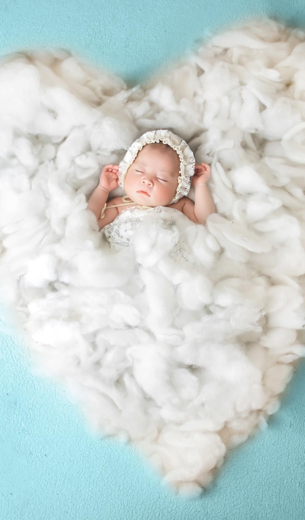 Новорожденный ребенок спит на белом мягком сердце на голубом фоне