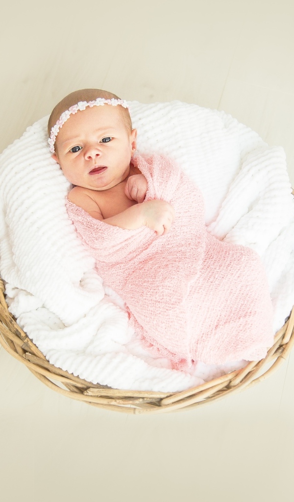 Новорожденная девочка в розовом покрывале в корзине