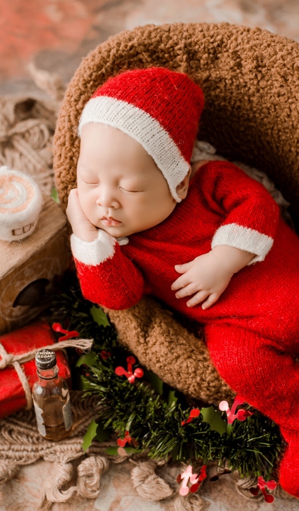 Спящий новорожденный ребенок в красном новогоднем костюме