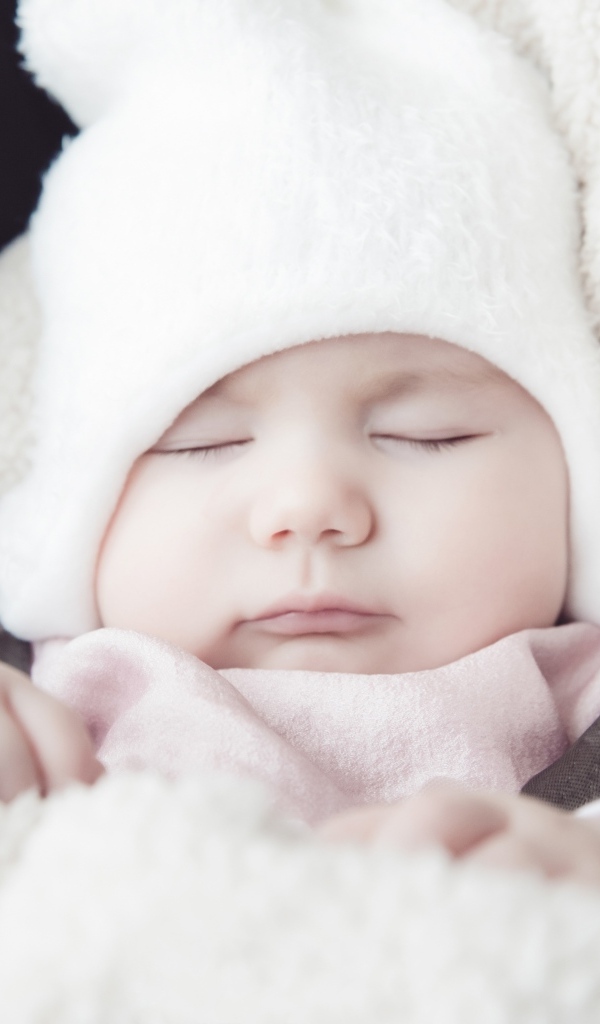 Спящий новорожденный ребенок в белой шапке