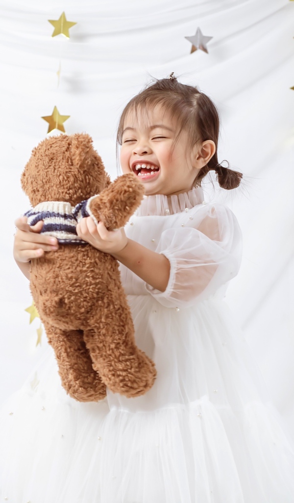 Улыбающаяся девочка азиатка с игрушечным медведем