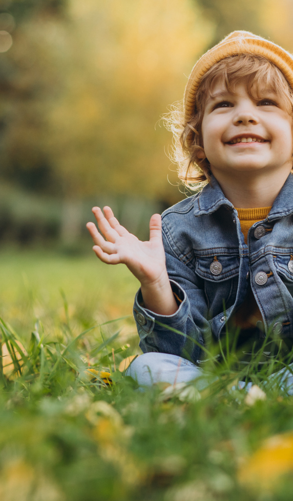 Улыбающийся ребенок сидит на траве