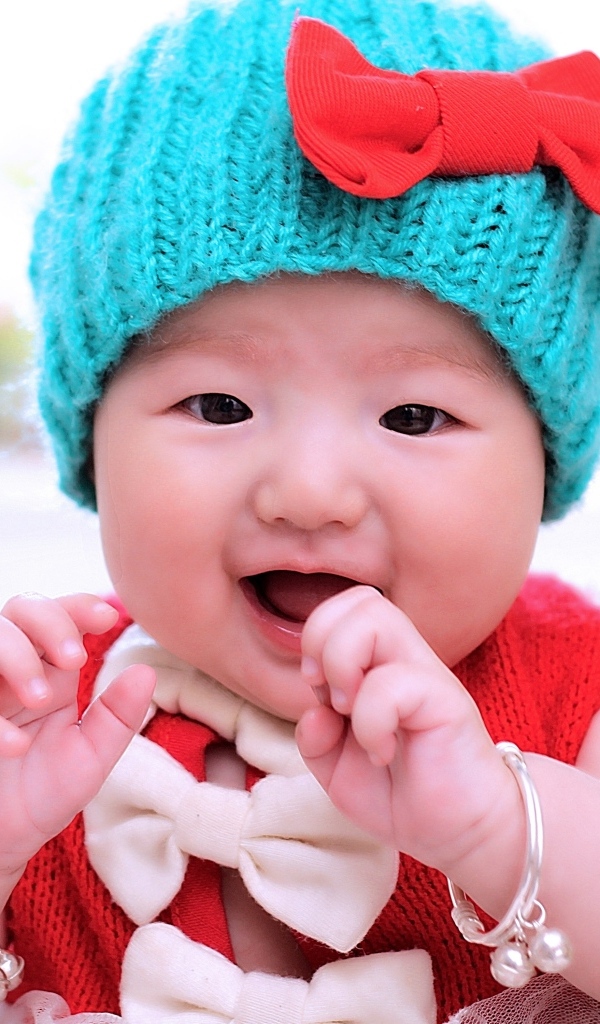 Улыбающаяся девочка в зеленой вязаной шапке