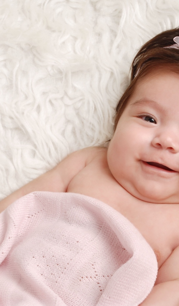 Улыбающаяся новорожденная малышка с бантом на голове