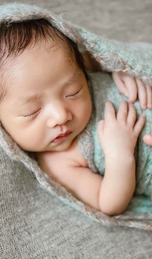 Крошечный новорожденный малыш на сером фоне