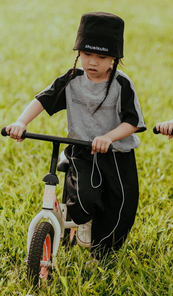 Две девочки с велосипедами на зеленой траве