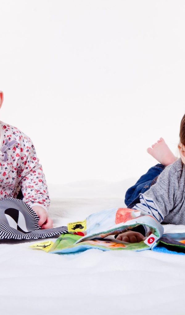 Два маленьких ребенка на кровати с мягкими книгами