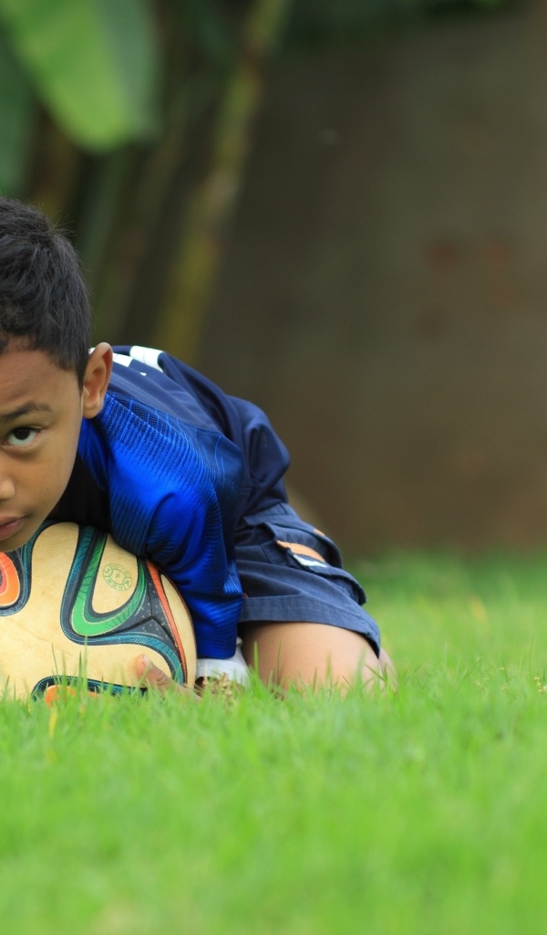 Мальчик юный футболист с мячом на поле