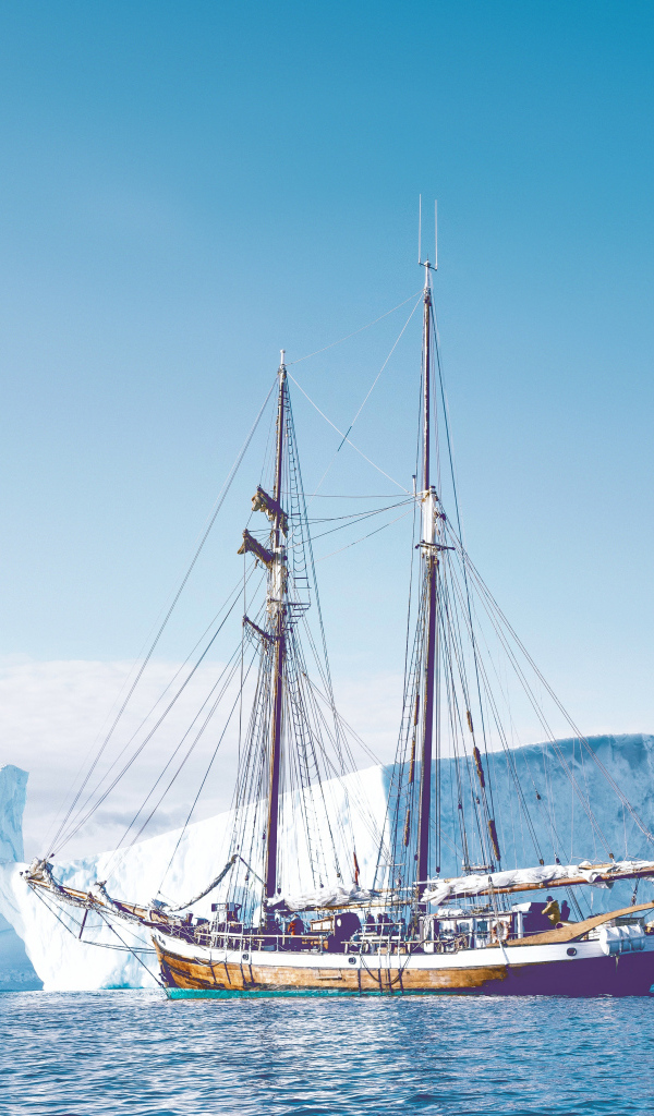 Большой корабль подплывает к голубому айсбергу в море