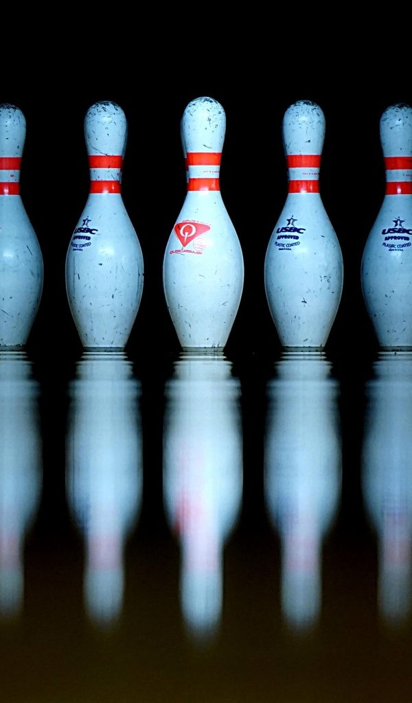 Кегли для боулинга отражаются в черной поверхности 
