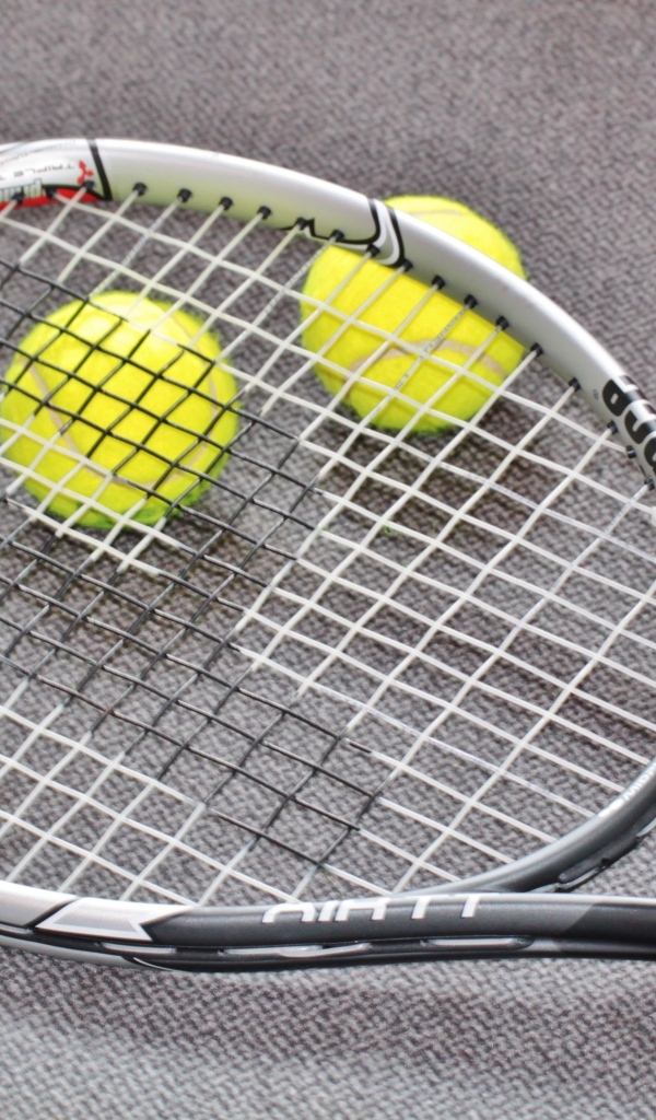 Ракетка и два мяча для тенниса на сером столе