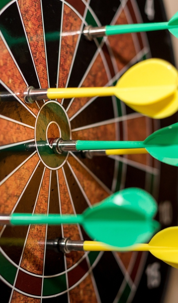 Желтые и зеленые дротики в мишени 
