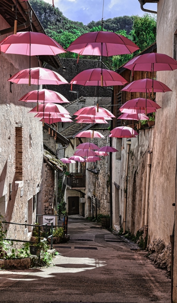 Розовые зонтики украшают узкую улицу