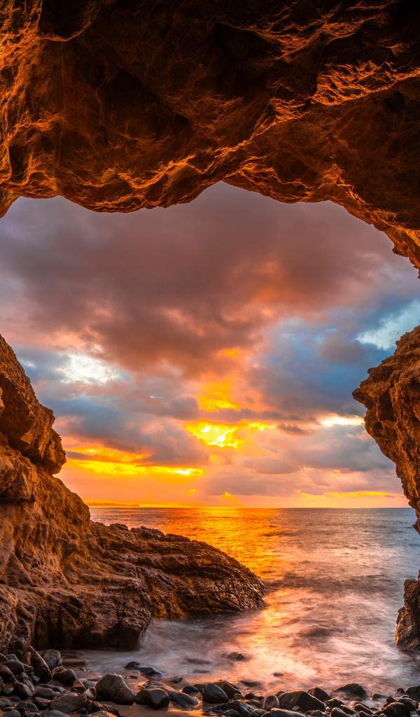 Арка в горе на закате солнца на пляже Малибу, США