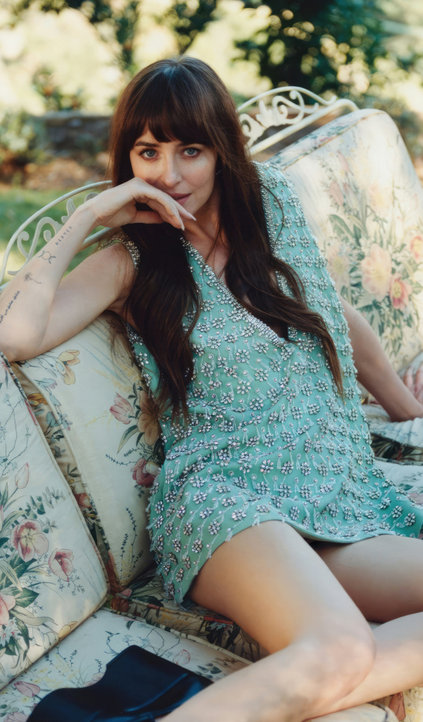 Актриса Дакота Джонсон в платье сидит на диване