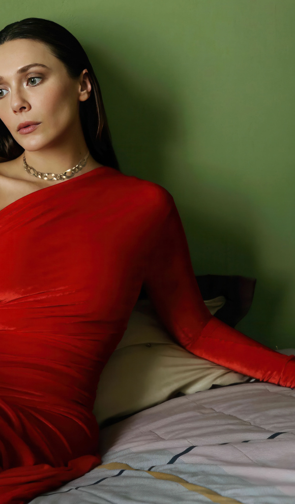 Актриса Элизабет Олсен в красном платье сидит на кровати