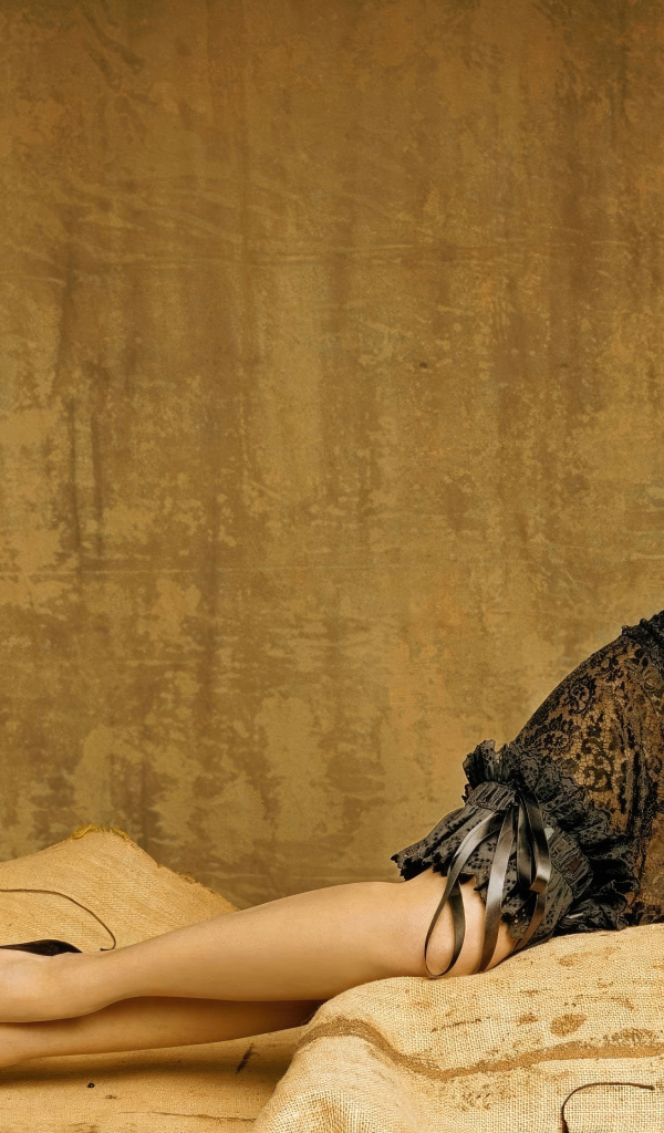 Актриса Эмми Россам в красивом черном платье лежит на диване