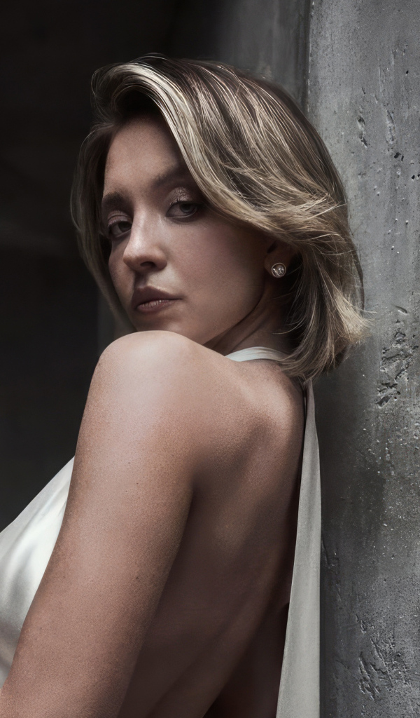 Актриса Сидни Суини стоит у серой стены