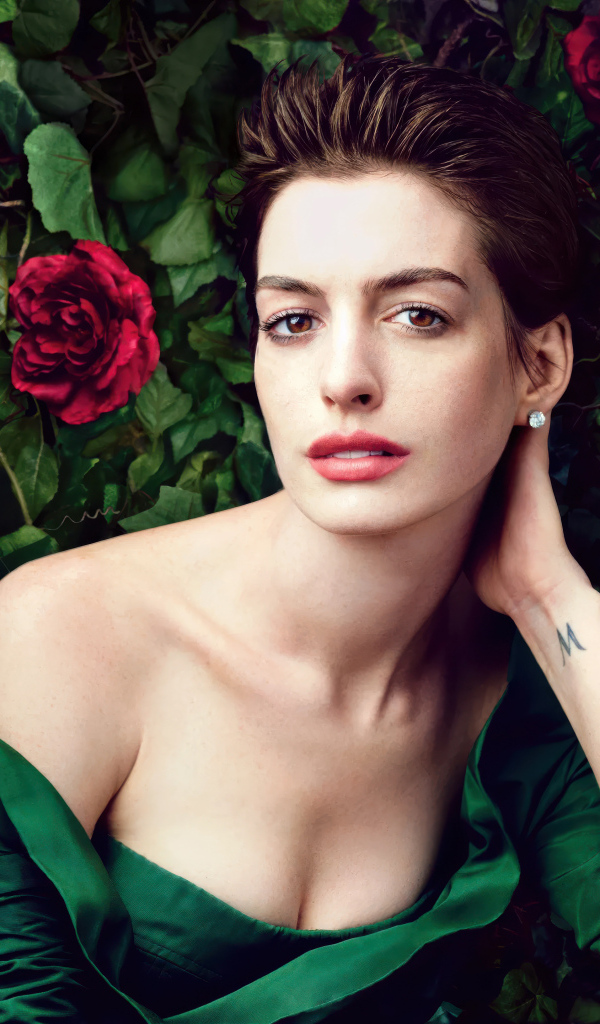 Красивая актриса Энн Хэтэуэй в зеленом платье на фоне роз