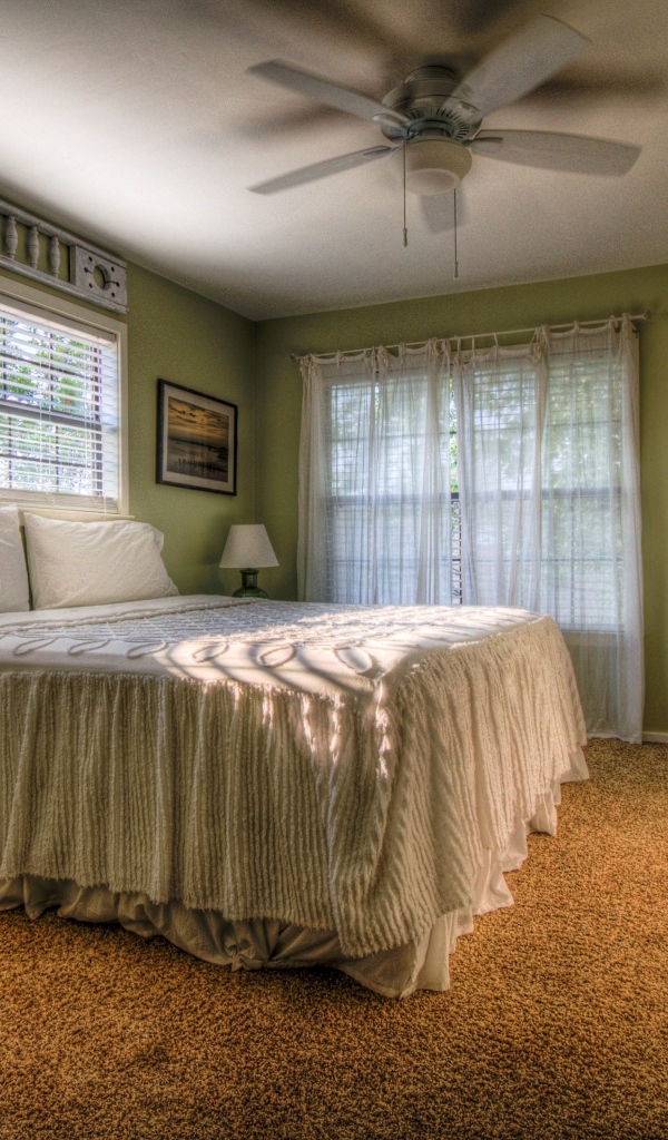 Спальня в зеленых тонах с высокой кроватью 