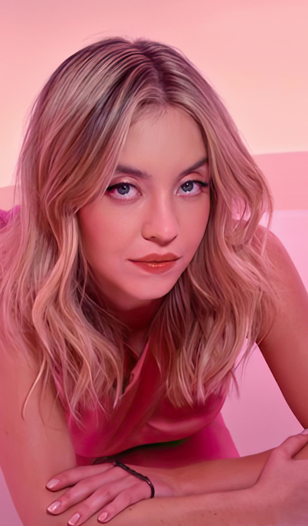 Милая блондинка Сидни Суини лежит на розовом фоне