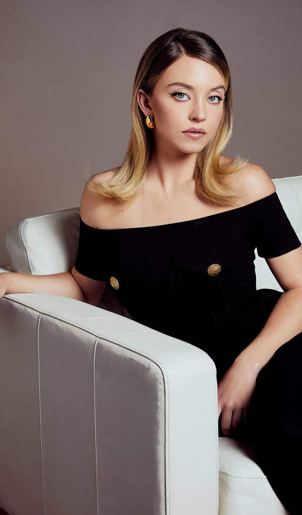 Милая девушка Сидни Суини в черном платье на диване