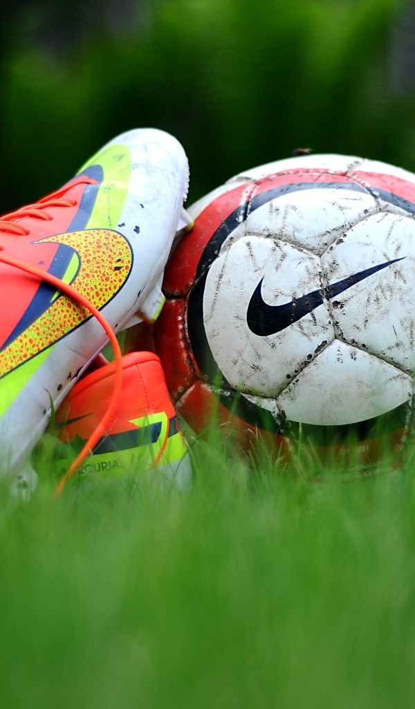 Футбольный мяч и бутсу на зеленой траве