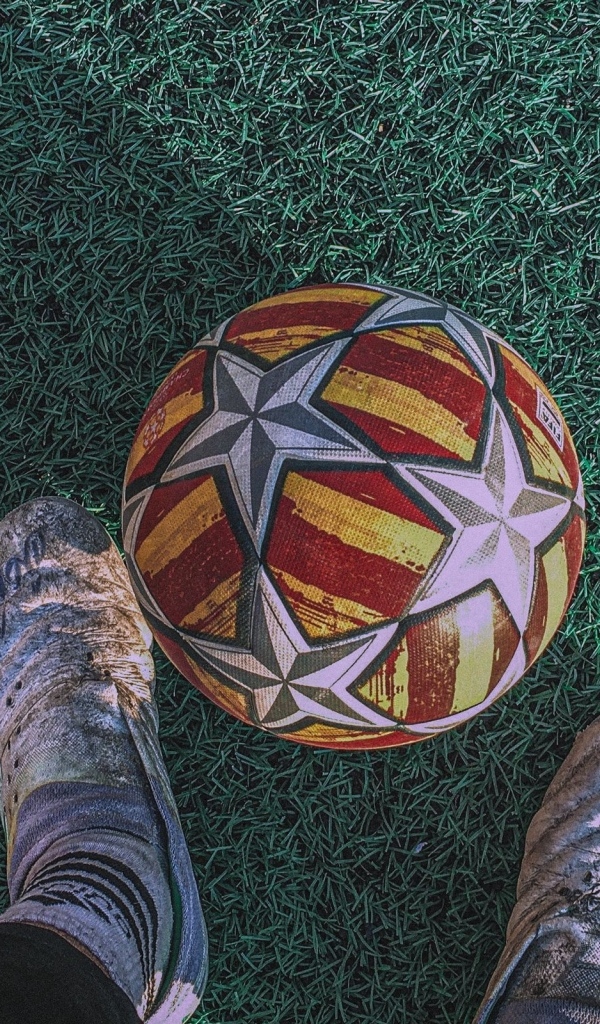 Футбольный мяч на зеленом поле с ногами футболиста