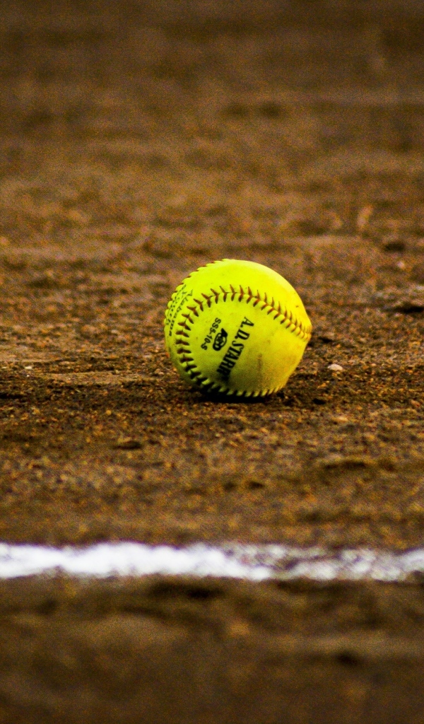 Желтый бейсбольный мяч на песке